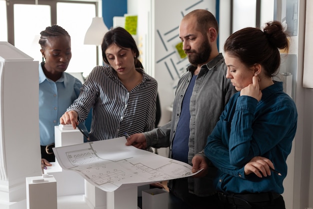 Photo d'une équipe d'architectes diversifiée sur un plan de construction Équipe d'architectes multiethniques travaillant sur un plan